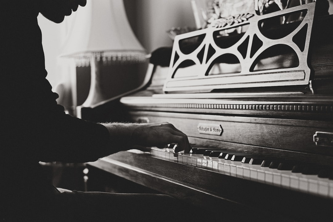Vintage piano player by Uniphonic greyscale photo of man playing spinet piano close-up photo