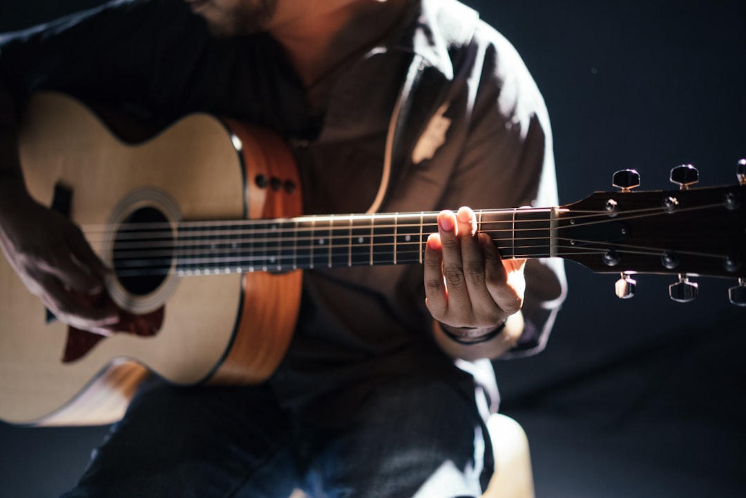 Acoustic guitar player in pale light by Uniphonic person playing guitar